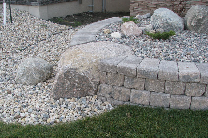 Roman Pisa garden wall with inset boulder around shrub bed on Lake Forest Road