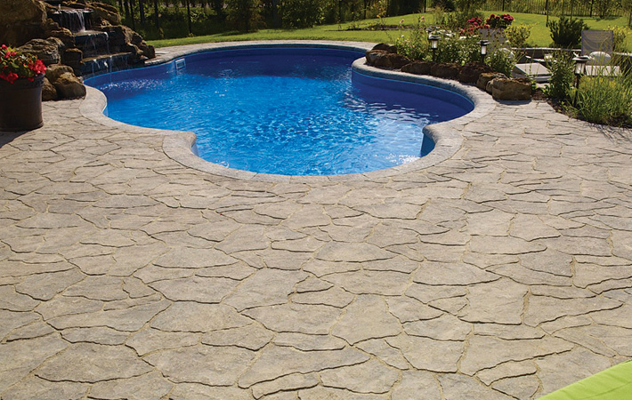 Flagstone stonework around in-ground swimming pool on landscaped yard